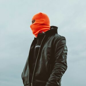 Cagoule technique orange portée avec une veste en cuir.